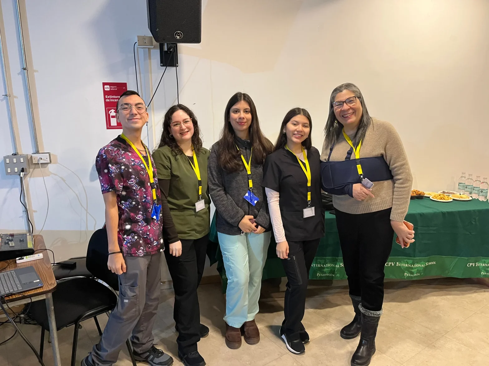 Group of five people wearing yellow lanyards, smiling for a photo at a conference or event.