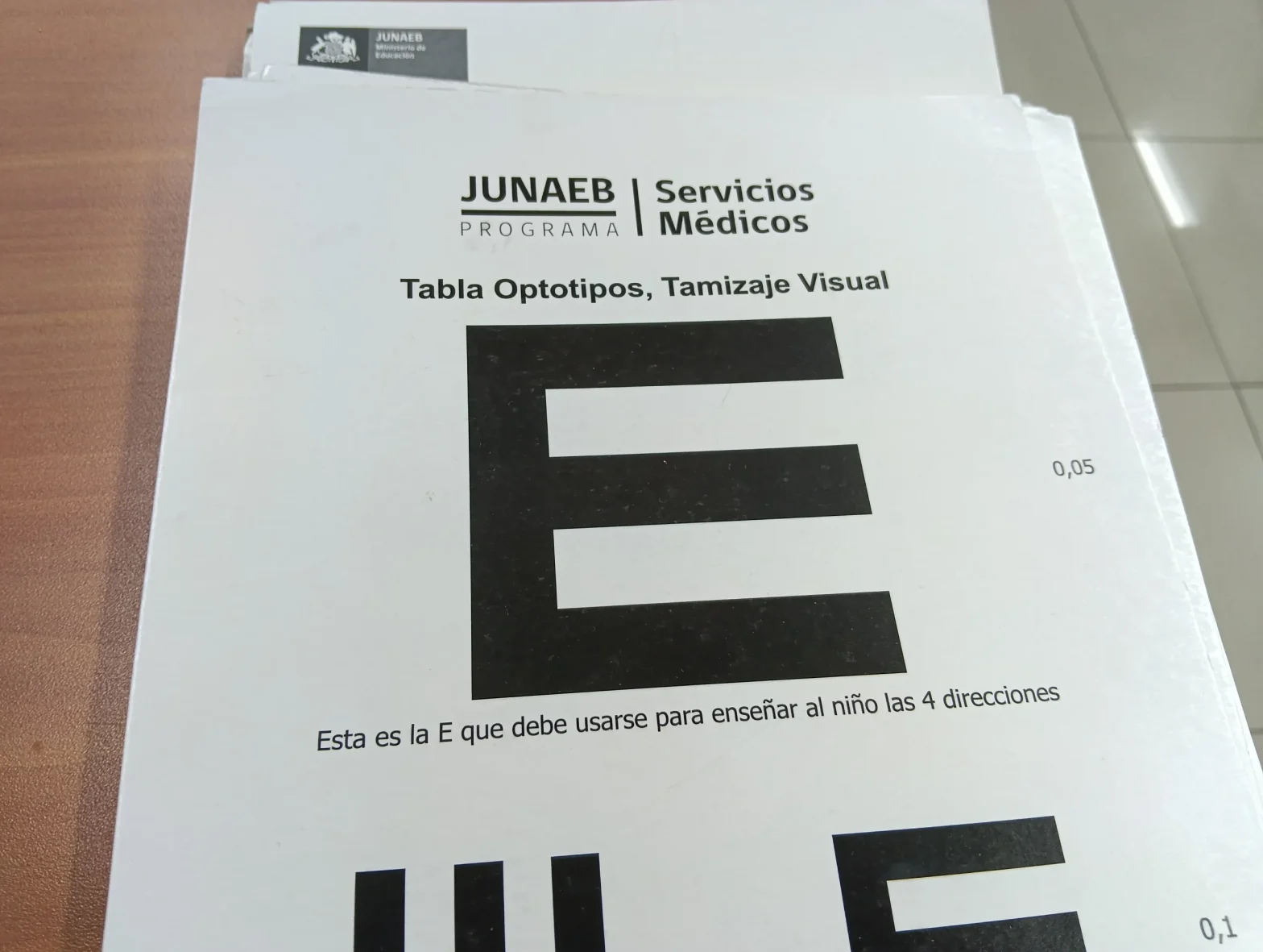 White sheet with JUNAEB logo and text 'Tabla Optotipos, Tamizaje Visual' and a large black 'E' optotype for vision screening (Spanish).