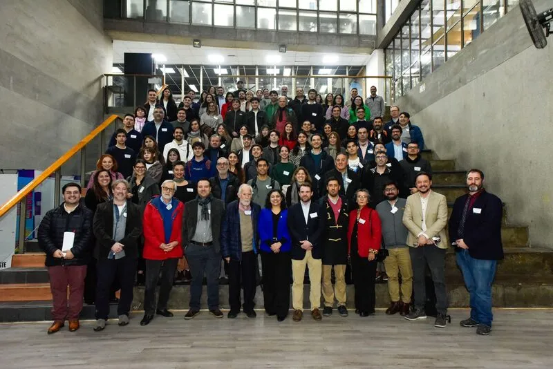 Large diverse group posing on a stairwell in an industrial-style interior during a conference or workshop event.