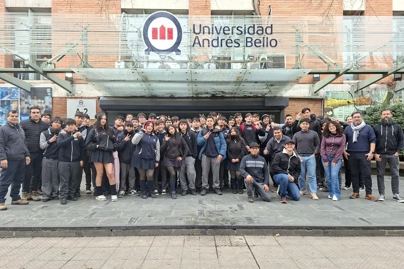 Group of students and staff posing for a photo outside Universidad Andrés Bello entrance.