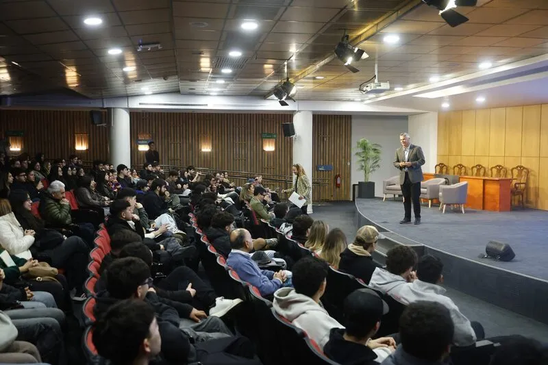 Speaker on stage addressing a large audience in a conference hall