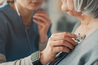 Healthcare professional uses a stethoscope to listen to an elderly patient's heart during a check-up.