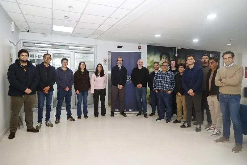 Group of adults standing in a hallway for a team or project photo, posing for the camera.